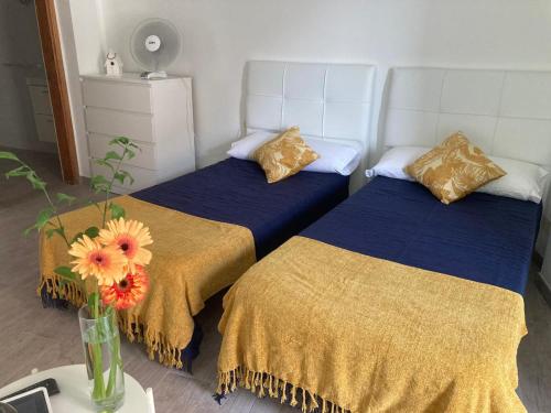 two beds in a room with a vase with flowers at Apartamentos Eva y Lola in Valle Gran Rey