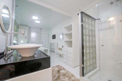 a white bathroom with a sink and a shower at Casa de Maria Suítes in Recife
