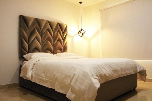 a bedroom with a bed with a headboard and a light at NOA Hotel Boutique in Tuluá