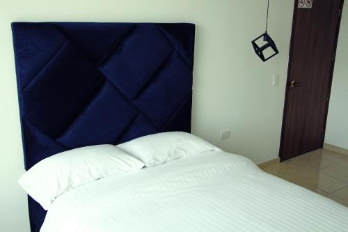 a bed with a blue headboard in a room at NOA Hotel Boutique in Tuluá