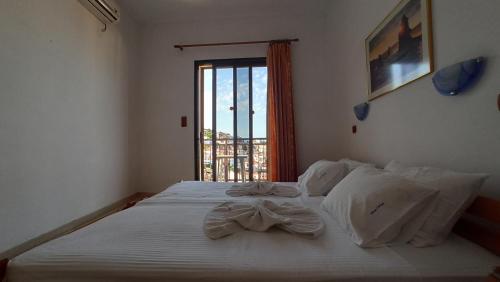 a bedroom with a large white bed with a window at Denise Hotel in Skopelos Town
