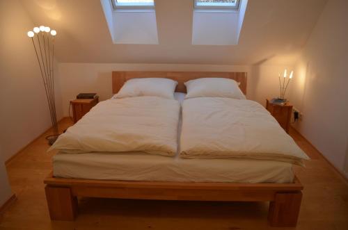 1 cama con sábanas blancas y almohadas en una habitación en Ferienwohnung Seefrieden, en Westensee