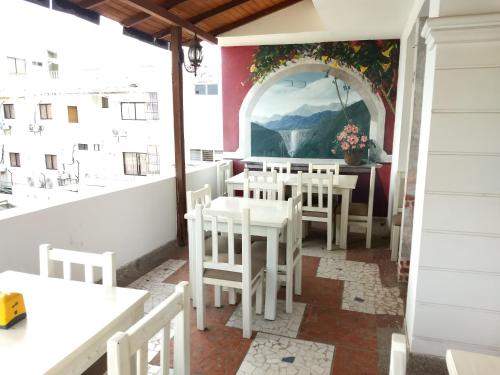a room with a table, chairs, and a painting on the wall at Hotel Tayromar in Santa Marta