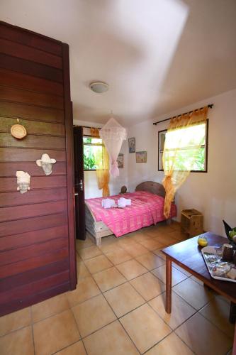 1 dormitorio con cama rosa y mesa en L'Ecomusee créole de la Guadeloupe, en Sainte-Rose
