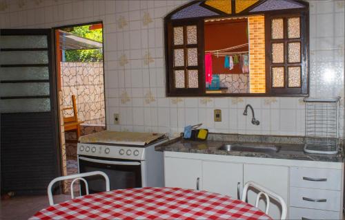 a kitchen with a table and a sink and a stove at Casa do Carlos, praia da Enseada Ubatuba-SP in Ubatuba