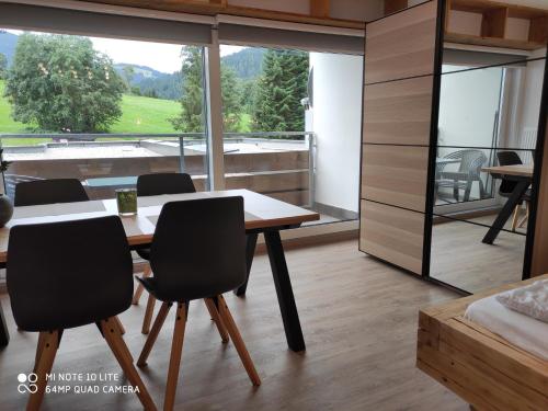 Cette chambre dispose d'une grande fenêtre et d'une table avec des chaises. dans l'établissement Berghof Apartment Bergwiese Top 31, à Ellmau