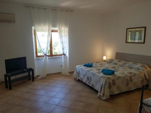 1 dormitorio con 1 cama, TV y ventana en Residence Argentiera, en Miniera dellʼArgentiera