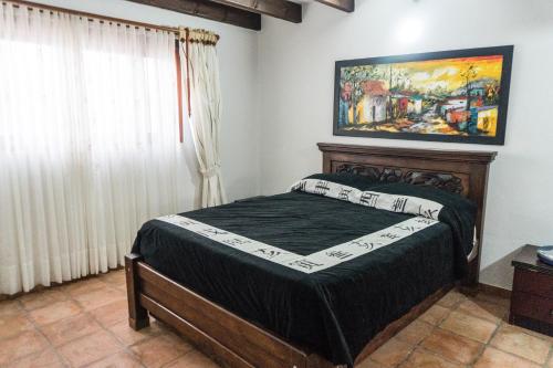 una camera da letto con un letto e un dipinto sul muro di Apartamento Madeiro a Villa de Leyva