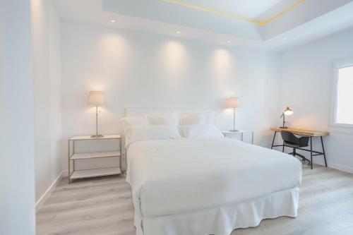Un dormitorio blanco con una cama blanca y dos lámparas. en Lauser City Suites, en Los Llanos de Aridane