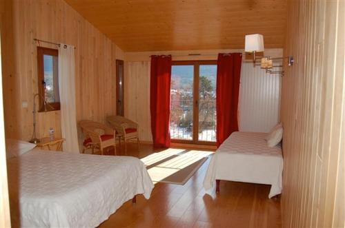 a bedroom with two beds and a window with red curtains at Maison Rouge in Plan dʼAups