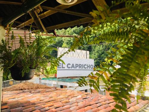 El Capricho by Rotamundos في Xicotepec de Juárez: لافته على حديقه فيها نباتات وارضيه طوب