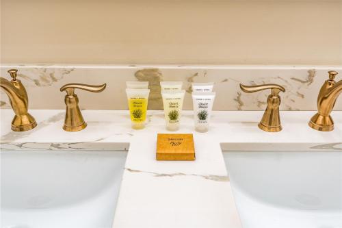 un bagno con rubinetti e bicchieri d'oro su un lavandino di The Alexandre a New Orleans