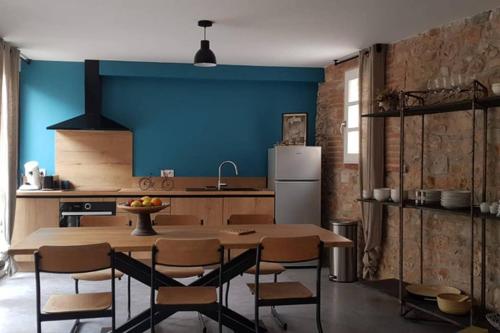 cocina con mesa, sillas y pared azul en Gîte de charme du Domaine Pagnon Frigoulette, en Torreilles