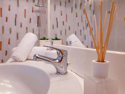 een wastafel in de badkamer met een kraan en een vaas met bamboe bij Kalliopi's apartment in Athene