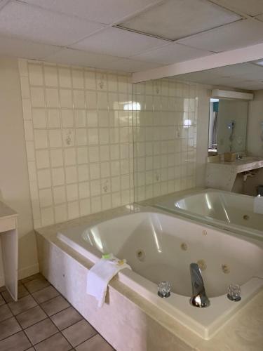 a bath tub in a bathroom with a mirror at Riverside Motor Lodge - Pigeon Forge in Pigeon Forge