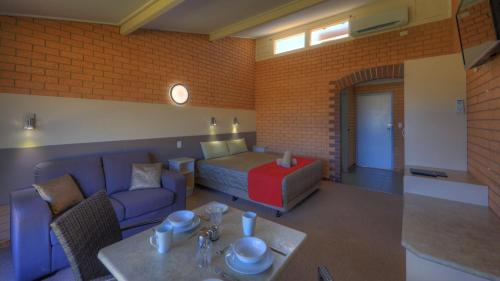 Zimmer mit einem Bett, einem Sofa und einem Tisch in der Unterkunft Tenterfield Motor Inn in Tenterfield
