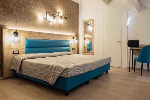 a bedroom with a blue bed and a desk at Cuneo Hotel in Cuneo