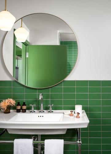 a green bathroom with a sink and a mirror at The Ruby Hotel in Round Rock