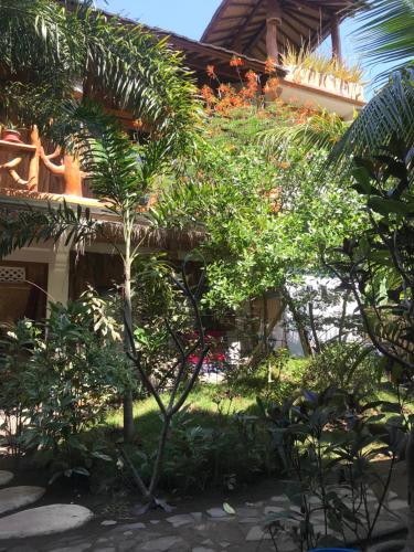 a garden in front of a house with trees at Sayang Mama Inn in Gili Air