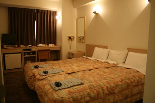 a hotel room with a large bed and a desk at Hotel Crown Hills Kumamoto in Kumamoto