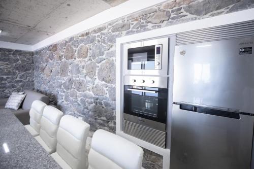 a kitchen with white chairs and a refrigerator at Stay in our cozy and wonderful Casa da Rosinha in Arco da Calheta