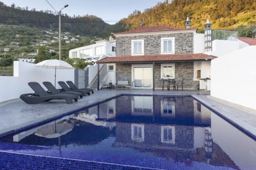 a villa with a swimming pool in front of a house at Stay in our cozy and wonderful Casa da Rosinha in Arco da Calheta