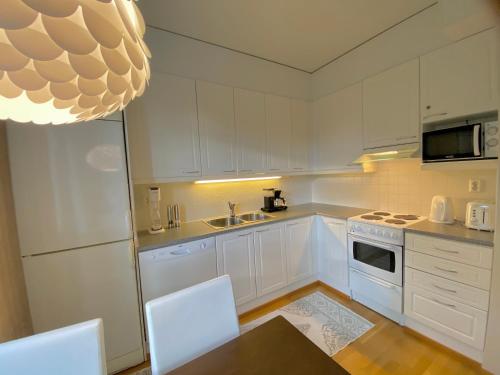 a kitchen with white cabinets and a table and chairs at Garden City Apartment, Helsinki - Vantaa Airport in Vantaa
