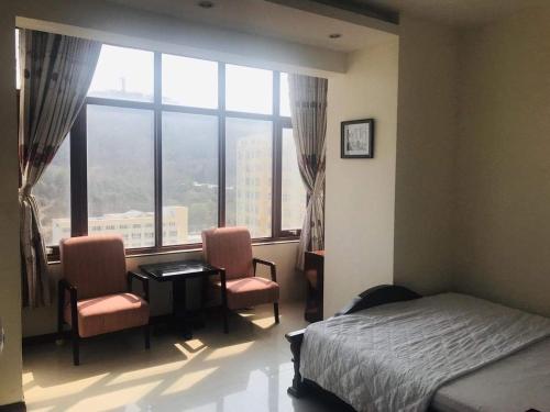 1 dormitorio con 1 cama, 2 sillas y ventana en Căn hộ Sơn Thịnh - Homestay, en Vung Tau