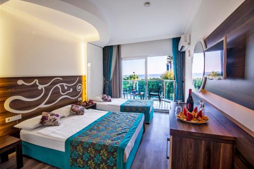 a hotel room with two beds and a balcony at Kleopatra blue hawai hotel in Alanya