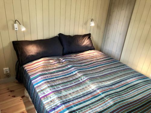 una cama con un edredón colorido en una habitación en Mysig nybyggd stuga nära hav och natur, en Klövedal