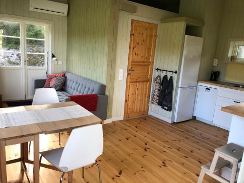 a kitchen and living room with a couch and a table at Mysig nybyggd stuga nära hav och natur in Klövedal
