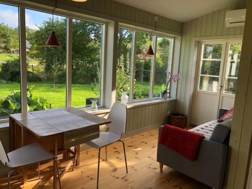 een eetkamer met een tafel, stoelen en ramen bij Mysig nybyggd stuga nära hav och natur in Klövedal