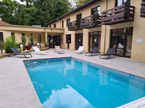 - une piscine en face d'une maison dans l'établissement Enzo Hôtels - ST Eloy Metz Amneville By Kyriad Direct, à Amnéville