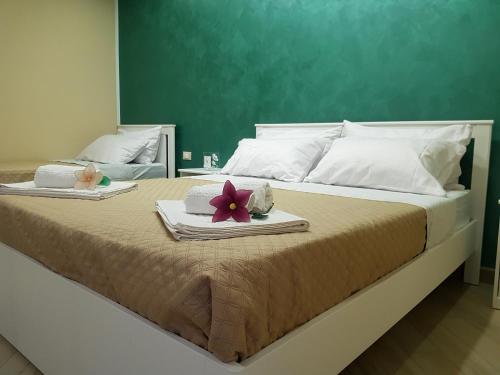 ein großes Bett mit zwei Handtüchern und einer Blume darauf in der Unterkunft Parsifal family room in Campofelice di Roccella