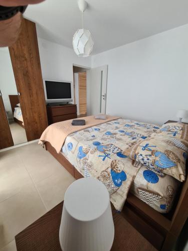 a bedroom with a bed and a table and a tv at SimpliCity Apartament in Tulcea