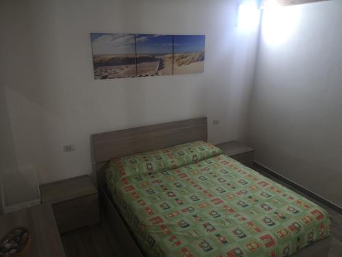 a bed in a bedroom with a picture on the wall at Casa Dema climatizzata con wifi in Martis