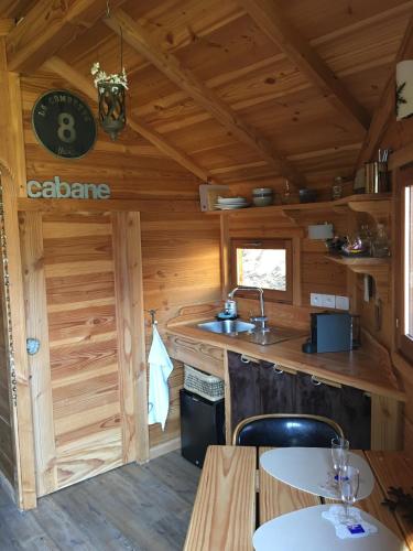a kitchen in a log cabin with a sink and tables at la Cabane dans les Arbres in Saint-Jean-dʼAulps
