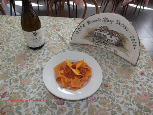 a plate of pasta on a table with a bottle of wine at Albergo Ristorante Turchino in Campo Ligure