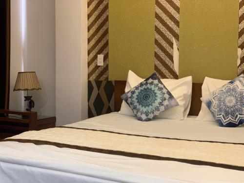 a bedroom with a bed with blue and white pillows at Hưng Thành Riverside Hotel in Thái Bình