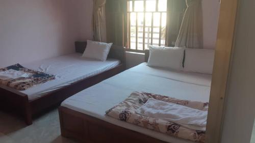 2 Einzelbetten in einem Zimmer mit Fenster in der Unterkunft Hải Phận Homestay in Ha Giang