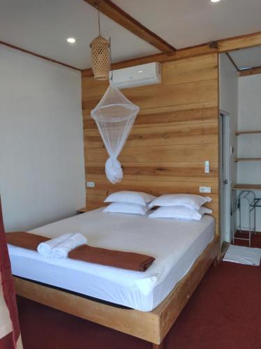 ein Schlafzimmer mit einem großen Bett und einer Holzwand in der Unterkunft Arto Moro Bunaken in Bunaken