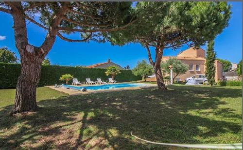 une cour avec une piscine et deux arbres dans l'établissement Gîte 3 étoiles 300m plage piscine privée grand jardin, à Châtelaillon-Plage