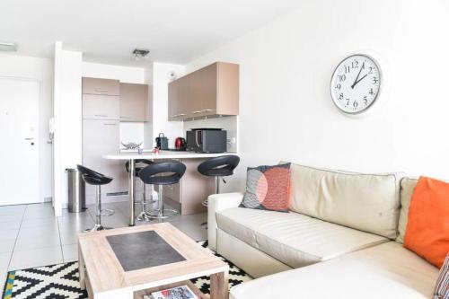 un salon avec un canapé et une horloge au mur dans l'établissement Appartement l'Opale - T2 48m avec parking à 300m du Lac d'Annecy, à Annecy
