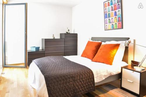 une chambre avec un grand lit avec des oreillers orange dans l'établissement Appartement l'Opale - T2 48m avec parking à 300m du Lac d'Annecy, à Annecy