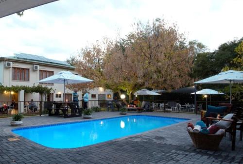 MiddelburgにあるCeltis Country Lodge & Restaurantのスイミングプール(椅子、テーブル、パラソル付)