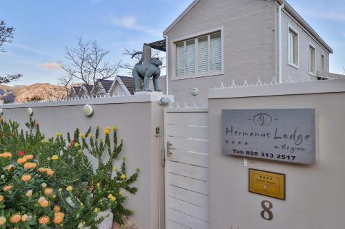 a building with a gate with a sign on it at Hermanus Lodge on the Green - Solar Power in Hermanus