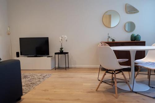 un salon avec une télévision, une table et des chaises dans l'établissement La Roseraie - Apartment 100m from Lake Annecy, à Annecy