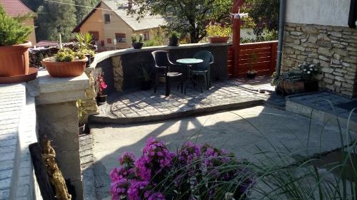 a patio with a table and chairs and flowers at Káli Apartman in Bakonybél