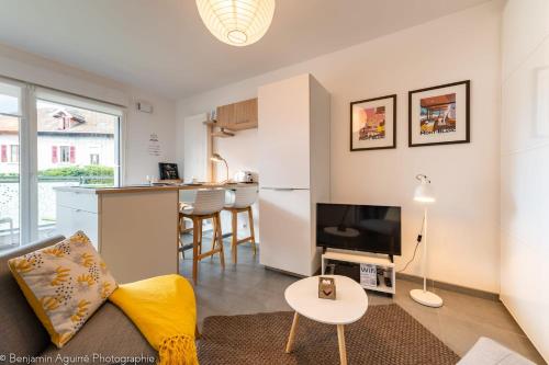 un salon avec un canapé et une télévision et une cuisine dans l'établissement Villa Aniciaca - Recent apartment with private and secure parking, à Annecy