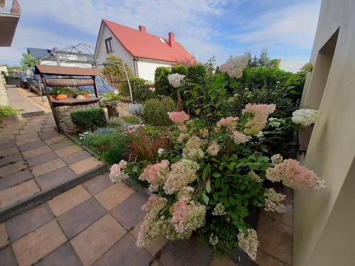 um jardim com flores rosas e brancas e uma casa em Apart - House em Sandomierz